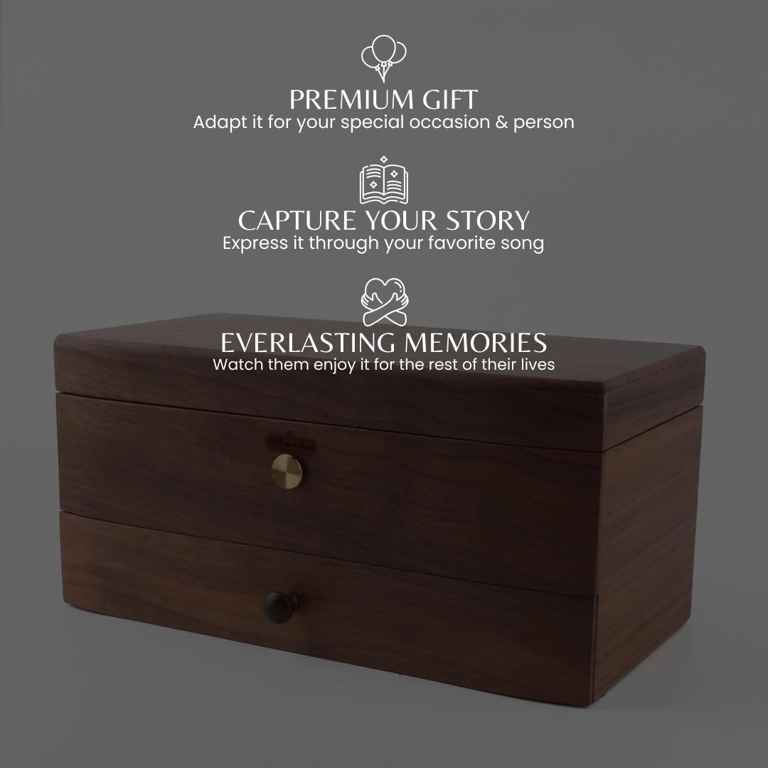 Enchanted Music Boxes 78-note walnut wood music box with a jewellery drawer and brass knob on a dark background.