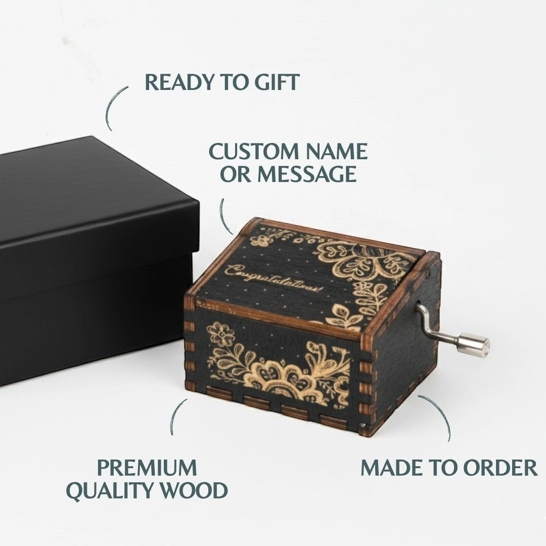 Enchanted Music Boxes hand-crank music box in black wood with intricate gold folk art floral engravings and custom text.