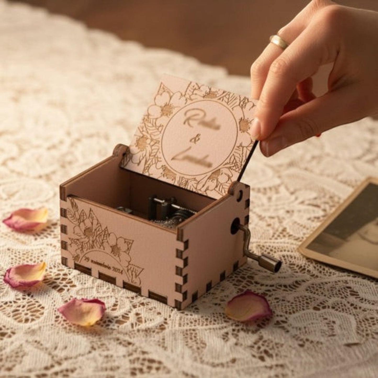 Enchanted Music Boxes cherry blossom plywood hand-crank music box with custom floral engraving on a lace tablecloth.