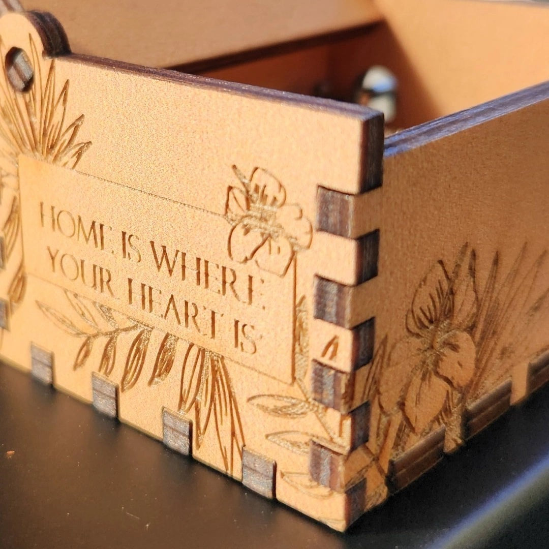 Enchanted Music Boxes plywood music box with laser-engraved hibiscus flowers and Home Is Where Your Heart Is text.