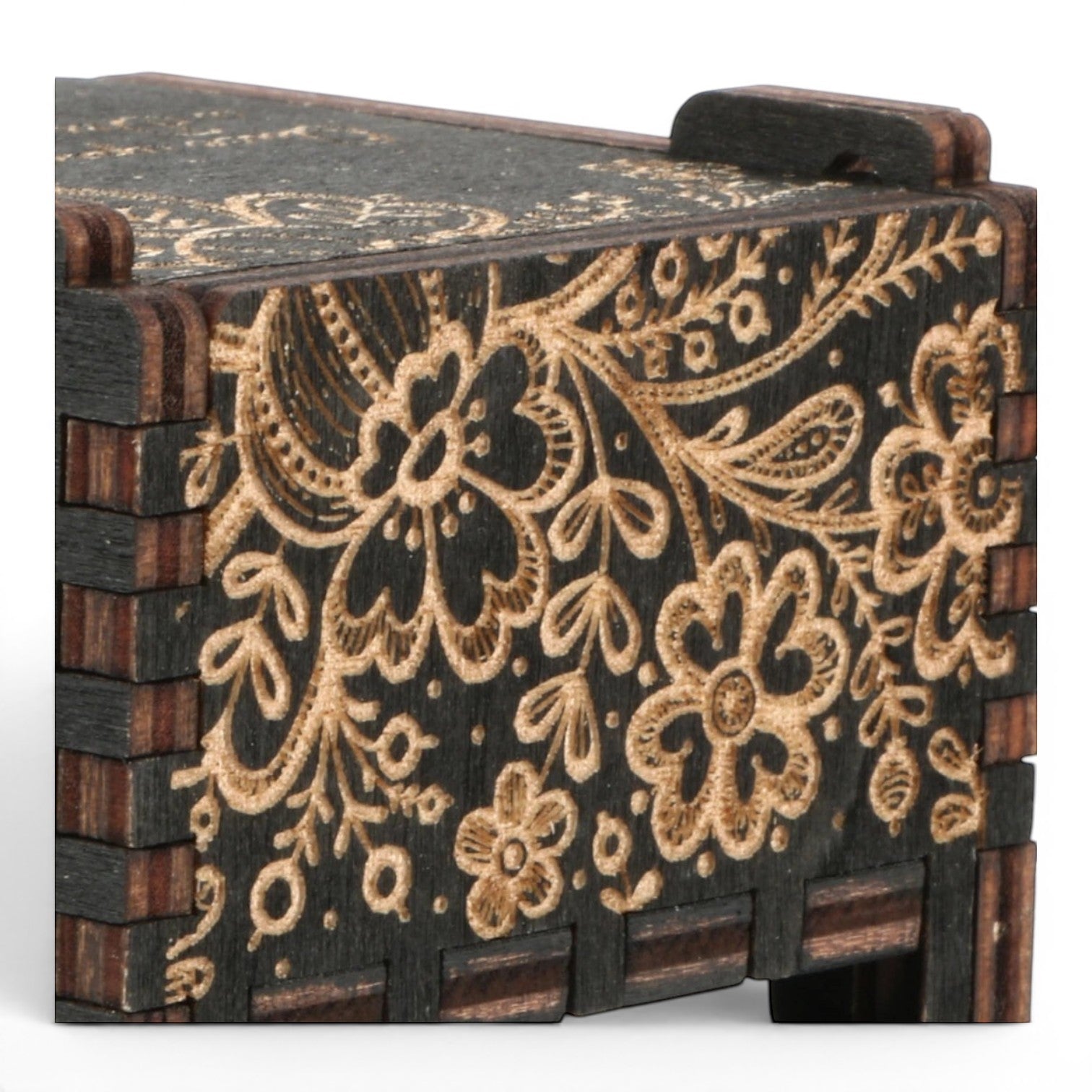 Detail view of Enchanted Music Boxes plywood music box featuring intricate black and gold floral folk art laser engravings