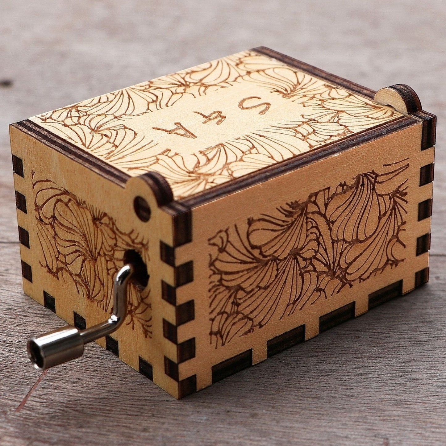 Enchanted Music Boxes hand-crank music box in laser-engraved plywood with floral patterns and custom initials on lid.