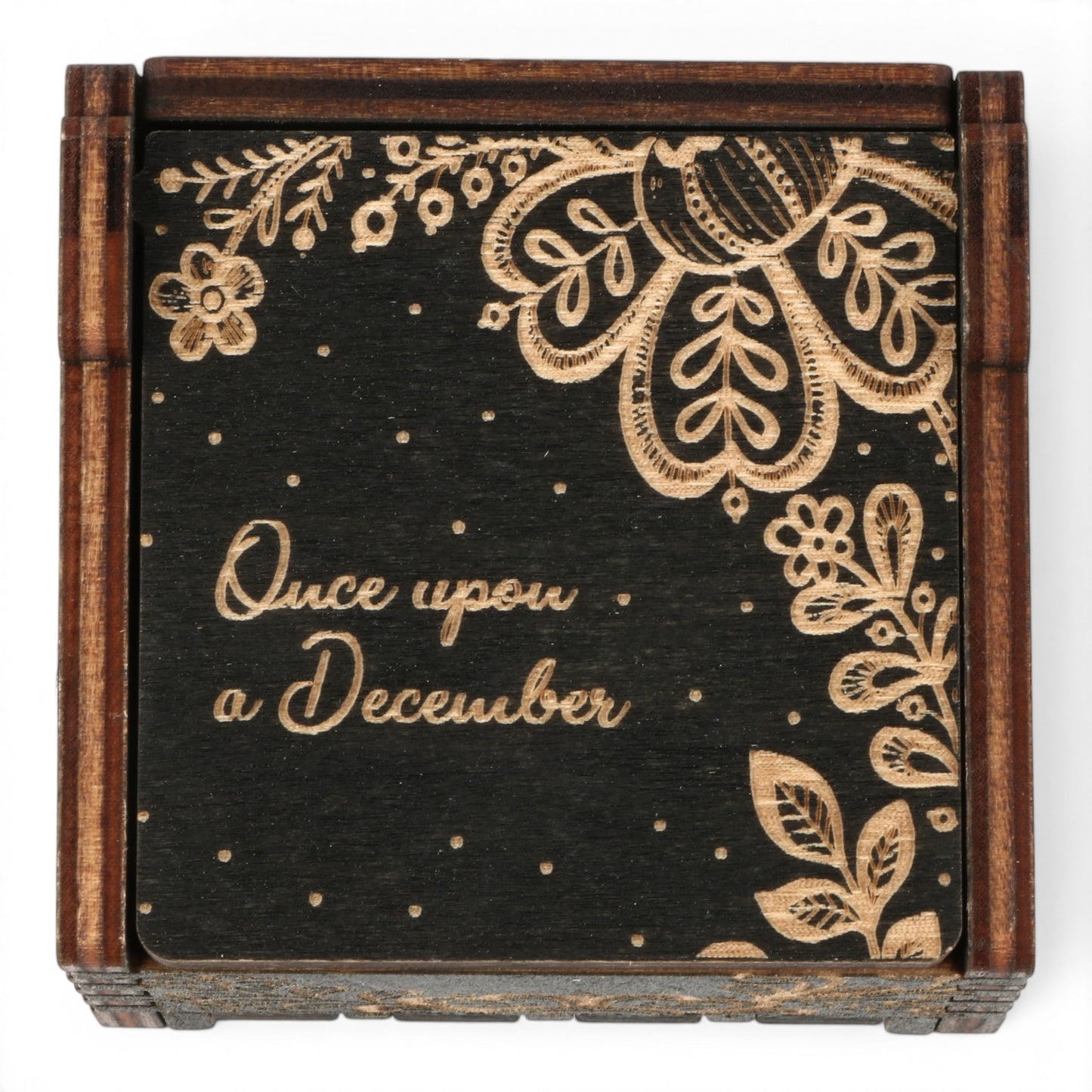 Top view of Enchanted Music Boxes wooden wind-up music box with black finish, floral laser-engraved lid, and Once upon a December text.