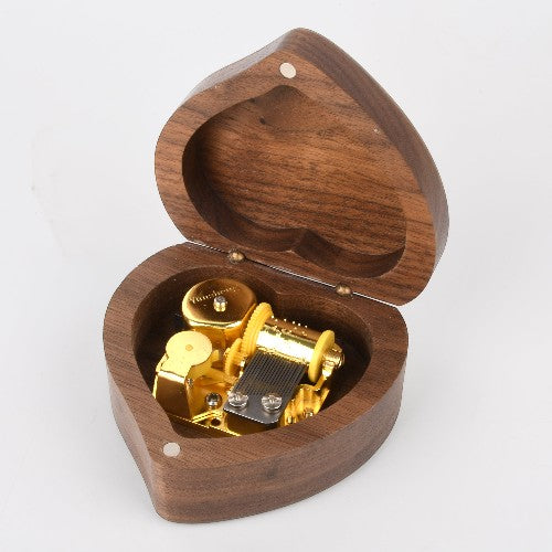 Enchanted Music Boxes heart-shaped wooden music box with an open lid revealing a gold-toned internal mechanism.