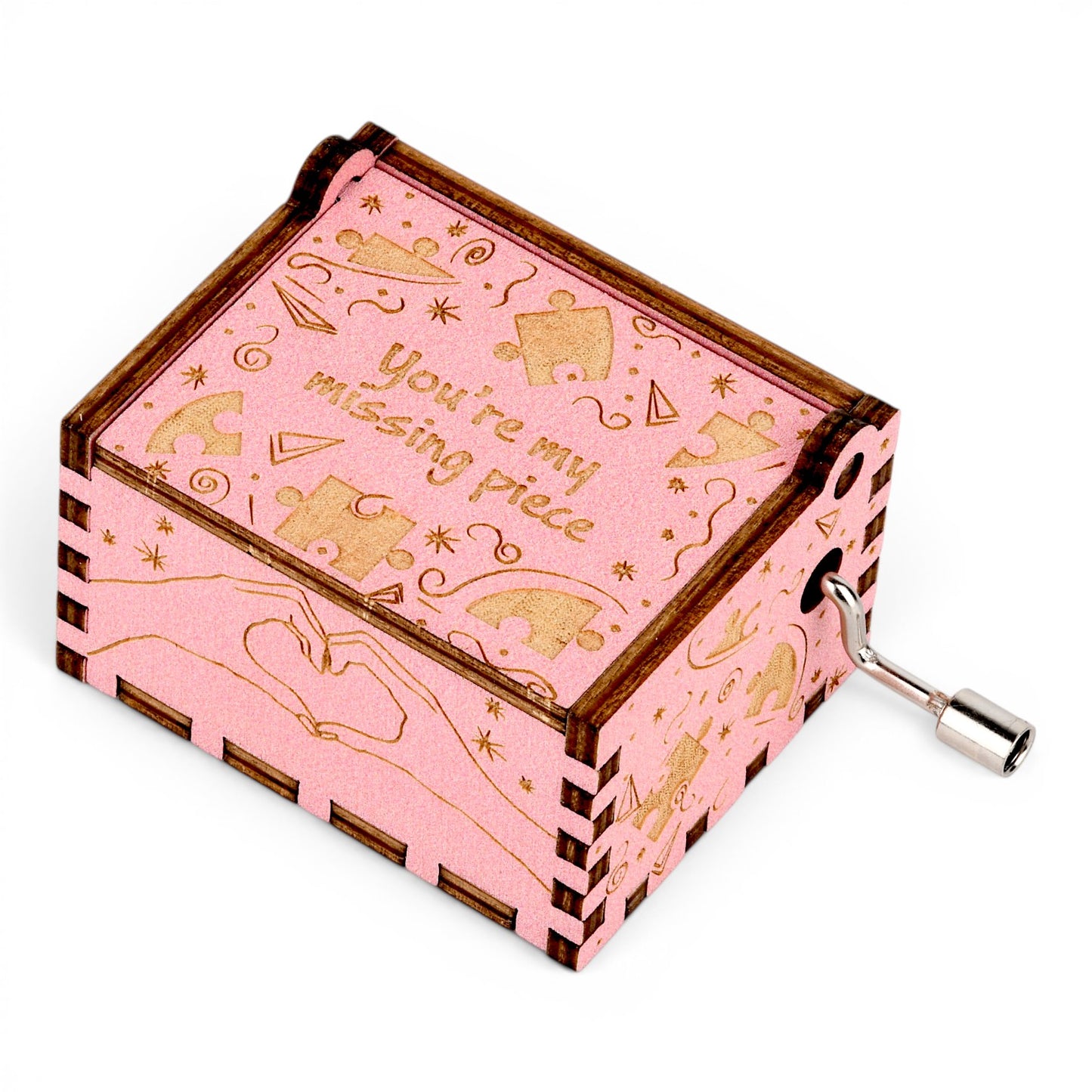 Enchanted Music Boxes pink plywood hand-crank music box with laser-engraved puzzle pieces and heart hands design.