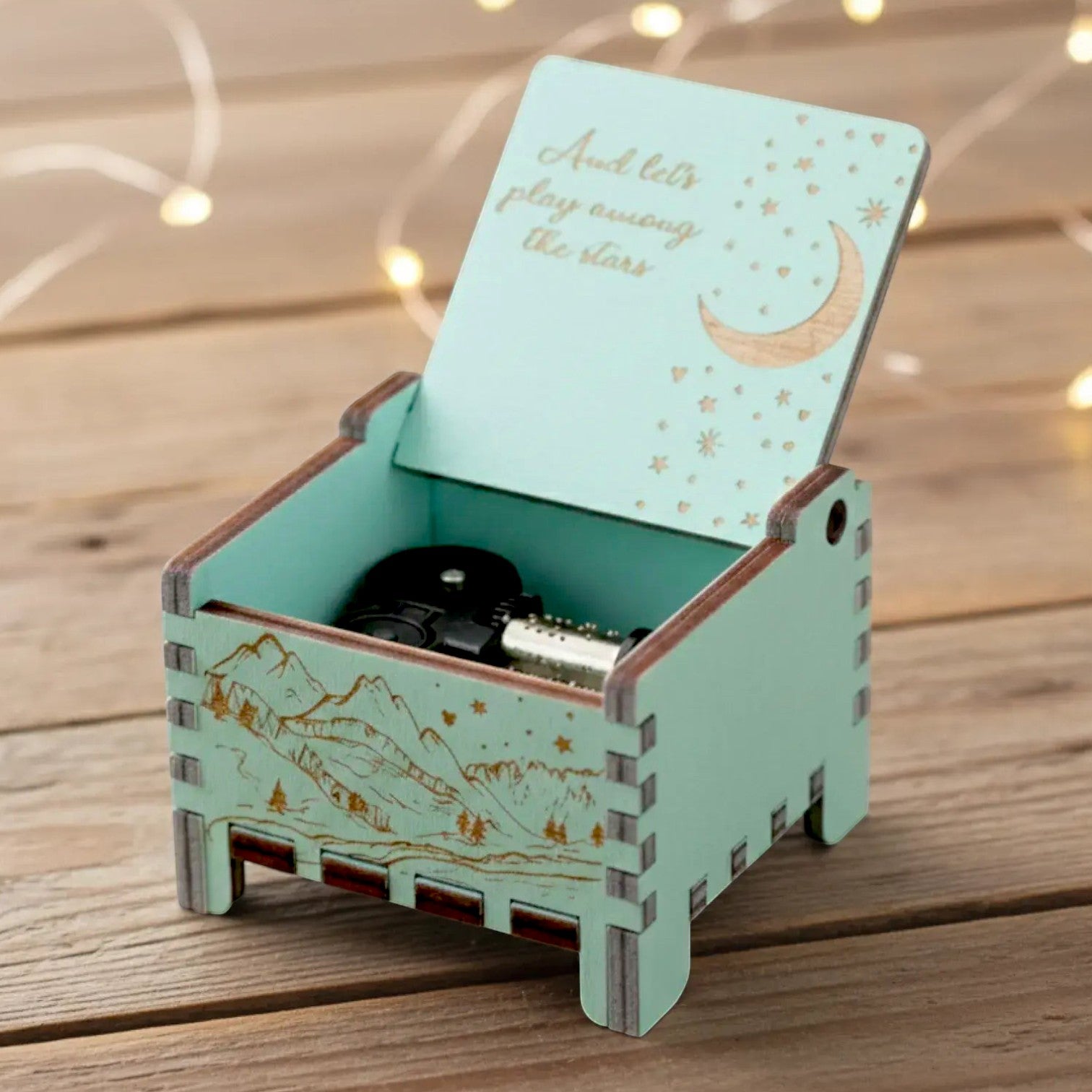 Enchanted Music Boxes wind-up music box in light blue wood with engraved moon, stars, and mountain landscape design.