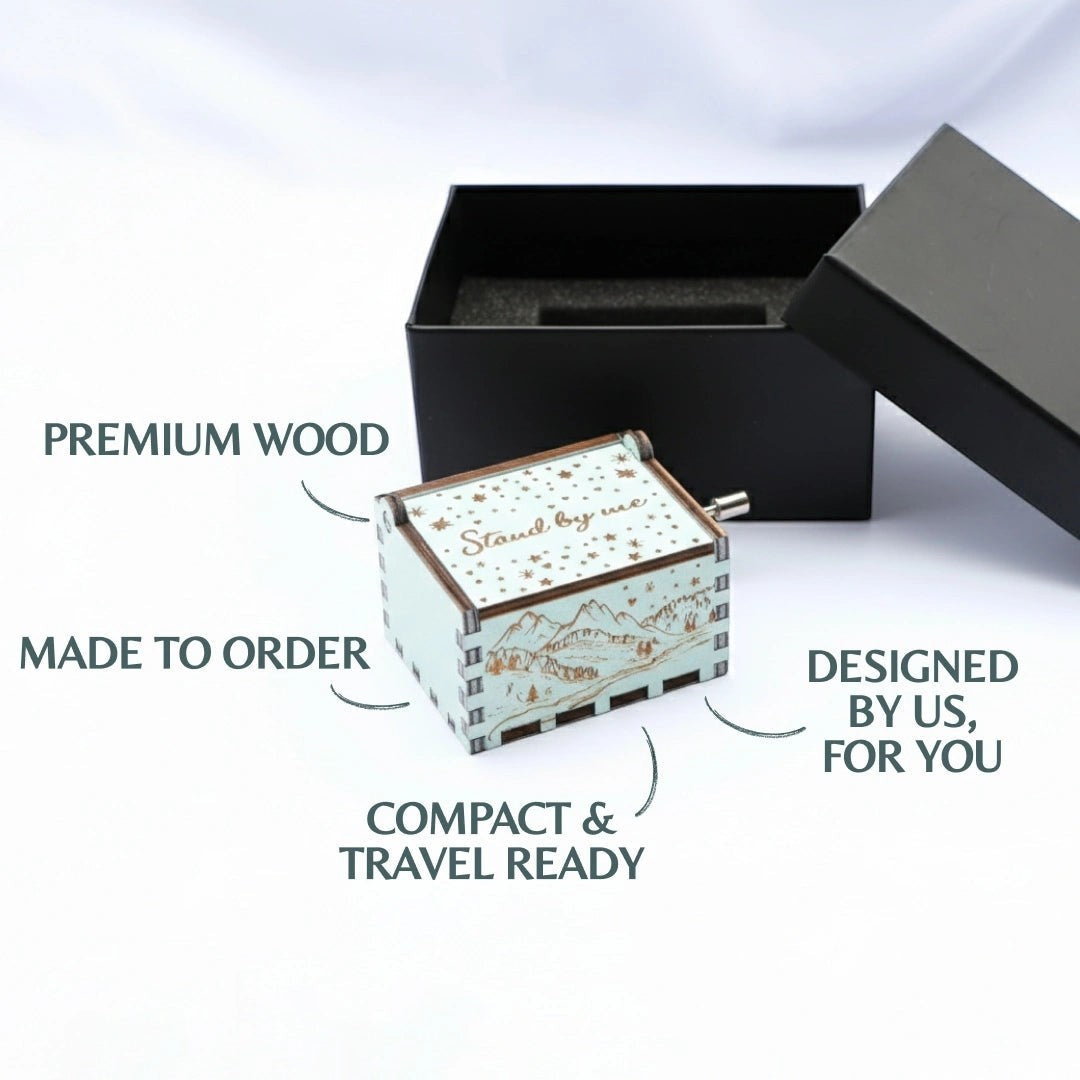 Enchanted Music Boxes Starry Night hand-crank music box in light blue plywood with mountain and star engravings.