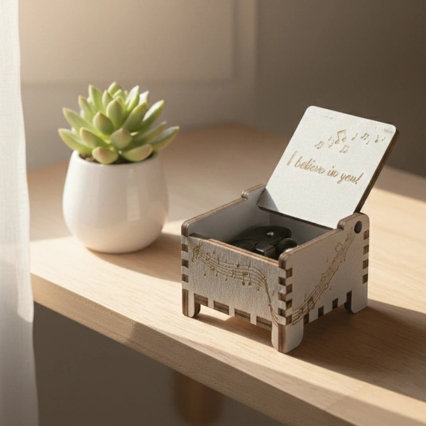 Enchanted Music Boxes wooden wind-up music box with musical note engravings and custom lid inscription on a desk.
